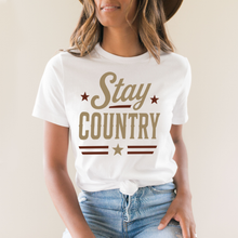 Load image into Gallery viewer, Person wearing a white t-shirt with 'Stay Country' text and stars on a plain background