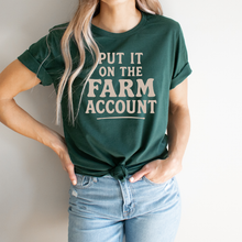 Load image into Gallery viewer, Person wearing a green t-shirt with text 'Put it on the farm account' against a plain background