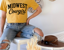 Load image into Gallery viewer, Person wearing a yellow 'Midwest Cowgirl' t-shirt sitting on a chair with a hat and sunglasses on a table.