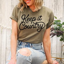 Load image into Gallery viewer, Person wearing a green t-shirt with 'Keep it Country' text and ripped jeans, standing against a neutral background.